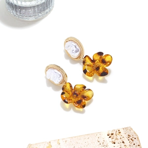Detail of baroque pearl and leopard print flower drop earrings on a stone prop