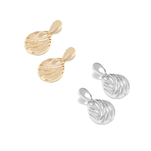 Detail view of gold and silver hollow oval earrings with striped texture and small crystals