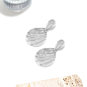 Detailed view of silver teardrop earrings with textured metal and sparkling rhinestones