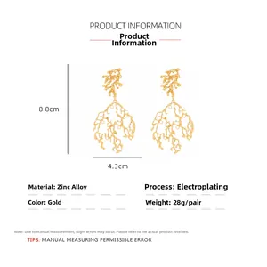 Dettaglio di grandi orecchini a corallo dorati con dimensioni di 8,8 cm per 4,3 cm