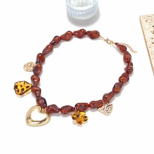 Collier en résine rétro avec cœur doré et pendentifs en ambre sur fond blanc épuré