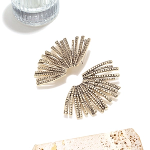 Luxurious gold leaf stud earrings with white rhinestones on natural stone background