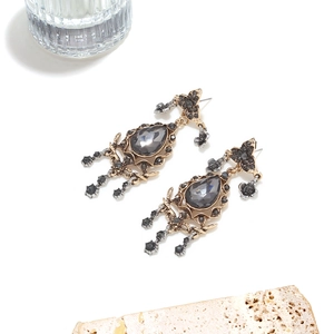 Detailed macro of vintage alloy drop earrings with grey gemstones and hollow floral motifs
