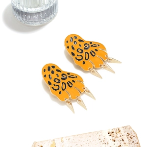 Dettaglio di orecchini a forma di artiglio leopardato in smalto arancione e oro