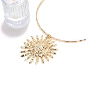 Close-up of golden sun pendant necklace featuring intricate facial relief and radiant rays