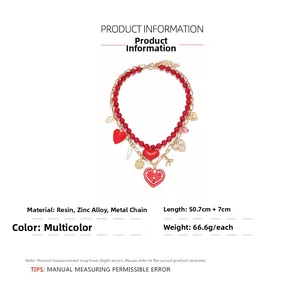 Detail of layered necklace featuring red resin beads with gold leaf and heart pendants