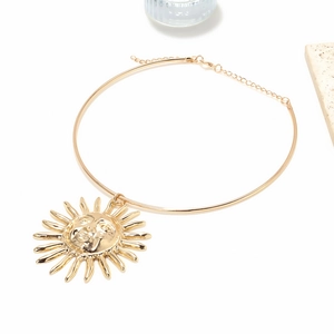 Golden sun pendant choker necklace with adjustable chain on minimalist textured background