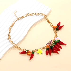 Détail du collier à maillons dorés orné de piments en verre rouge et de fleurs colorées