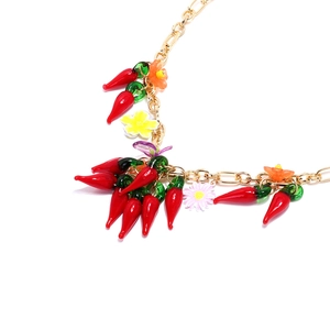 Collier avec pendentif piment en verre et fleurs sur chaîne dorée fond blanc