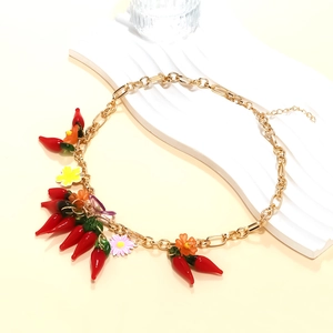 Détail du collier chaîne dorée avec pendentifs piments rouges et petites fleurs