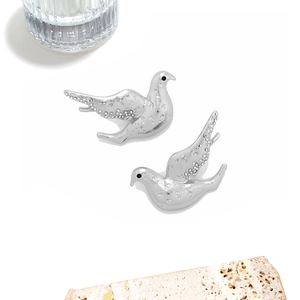Vue détaillée de boucles d'oreilles oiseaux argentées avec texture diamantée sur pierre