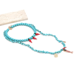 Detail of layered turquoise beaded necklace with red chili pendants and golden charms