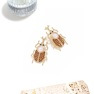 Vintage beetle stud earrings with golden alloy, white pearl, and amber rhinestone detail