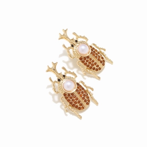 Close-up of vintage beetle earrings with amber rhinestones and white pearls set in gold alloy