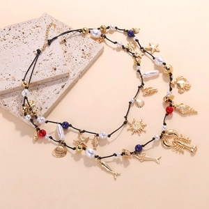 Dettaglio della collana boho oceano con ciondoli dorati a forma di aragosta, pesce e conchiglia