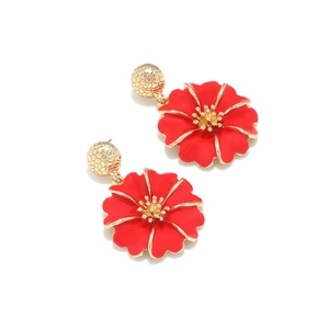Vue macro détaillée de boucles d'oreilles fleur en émail rouge et bordure en métal doré