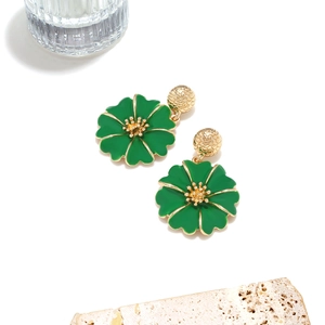Détail macro de boucles d'oreilles fleurs en émail vert avec bordure dorée