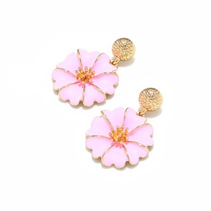 Détail de boucles d'oreilles fleurs en émail rose avec clous dorés et bords pétale