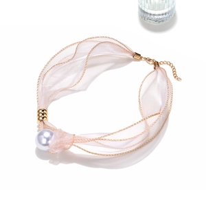 Dettaglio di un choker in organza rosa con un grande ciondolo di perla e gancio d'oro