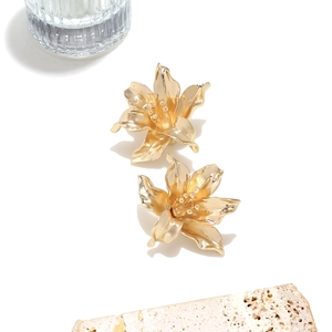 Detailed macro shot of vintage gold flower earrings on white background and stone decor