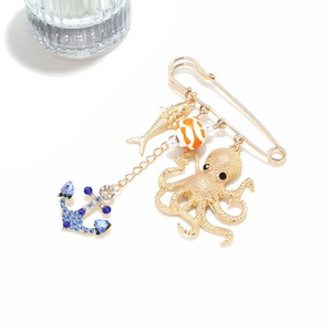 Detail of nautical charms featuring a gold octopus, fish, and anchor on a safety pin brooch