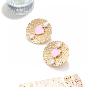 Vintage gold hammered earrings with pink heart and white stones on stone display