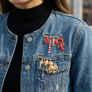 Exaggerated metal lobster and seahorse brooch pins on denim for waist adjustment