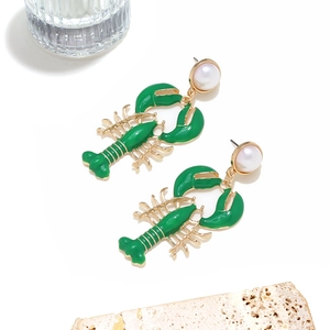 Detail of green lobster earrings with gold metal legs and elegant faux pearl studs