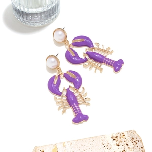 Detail of purple enamel lobster earrings with white pearl studs on a white background