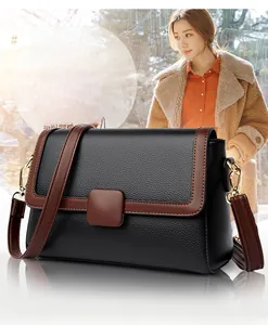 Detailed view of women's black litchi pattern leather crossbody bag with brown flap