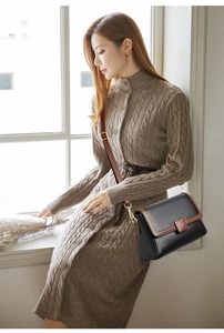 Detail of black pebbled leather crossbody bag with brown contrast flap and metal buckle