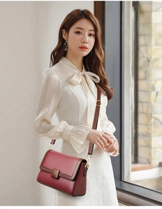 Detail of burgundy crossbody bag with litchi texture and golden magnetic hardware