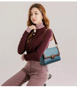 Detail of blue textured leather shoulder bag with brown trim on a fashion model