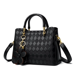Sac à main matelassé noir élégant avec finitions dorées et breloque fleurie