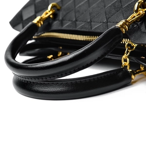 Gros plan sur la texture en cuir noir matelassé avec chaîne en métal doré du sac à main