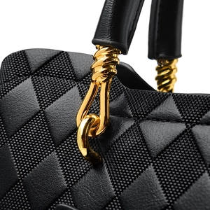 Détail de sac bandoulière matelassé noir avec finitions métalliques dorées chic
