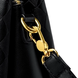 Détail du fermoir mousqueton doré et des ferrures gravées sur un sac en cuir matelassé noir
