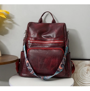 Detail of burgundy PU leather backpack featuring bohemian style colorful woven shoulder strap