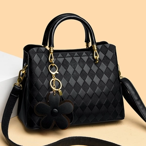 Détail du sac matelassé noir avec finitions dorées et breloque fleurie en cuir souple