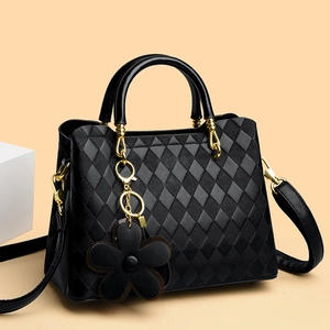 Détail du sac à main matelassé noir avec accessoires dorés et pendentif en fleur