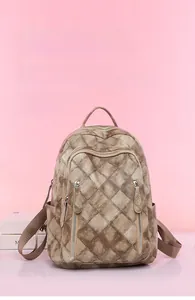 Close-up of vintage brown plaid backpack with multiple zipper pockets on a pink background