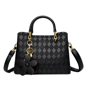 Détail d'un sac à main matelassé noir avec finitions dorées et pendentif fleur