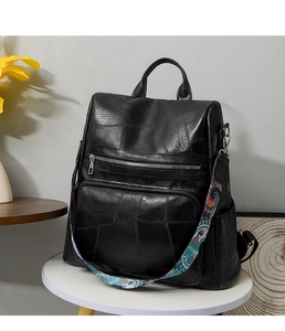Detail of black PU leather backpack with vintage bohemian style colorful woven shoulder strap