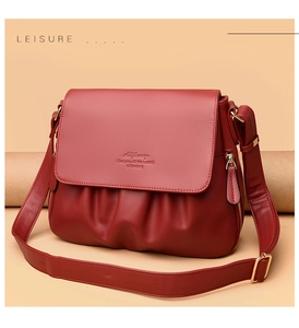 Dettaglio della borsa a tracolla rosso scuro con grana litchi e design plissettato con oro