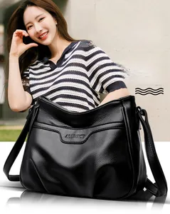 Detail shot of black litchi pattern leather shoulder bag on model showing fine texture