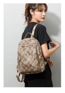 Detail of khaki vintage backpack with diamond pattern and side zip pockets on model