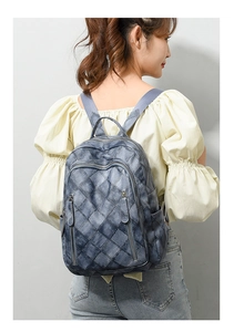 Detail of grey-blue woven texture faux leather backpack on a model showing back view
