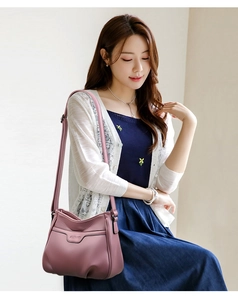 Close-up of pink embossed leather crossbody bag with adjustable strap on a model