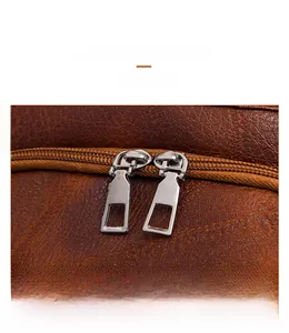 Detail of silver-tone dual metal zippers on brown lychee texture PU leather backpack