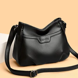 Detail view of black lychee grain leather crossbody bag with adjustable strap and logo